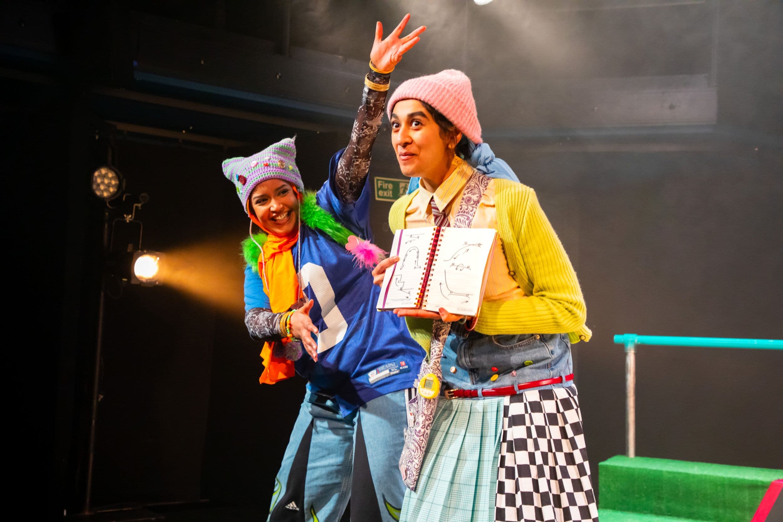 Two performers in colorful costumes on stage with bright lighting