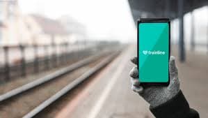 Gloved hand holding smartphone with trainline app at station