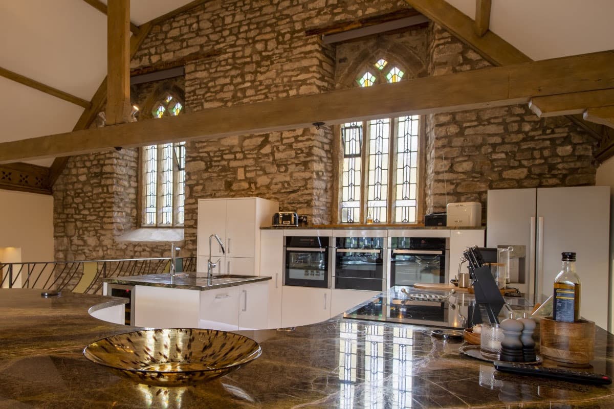 Rustic kitchen with stone walls, wooden beams, and modern appliances