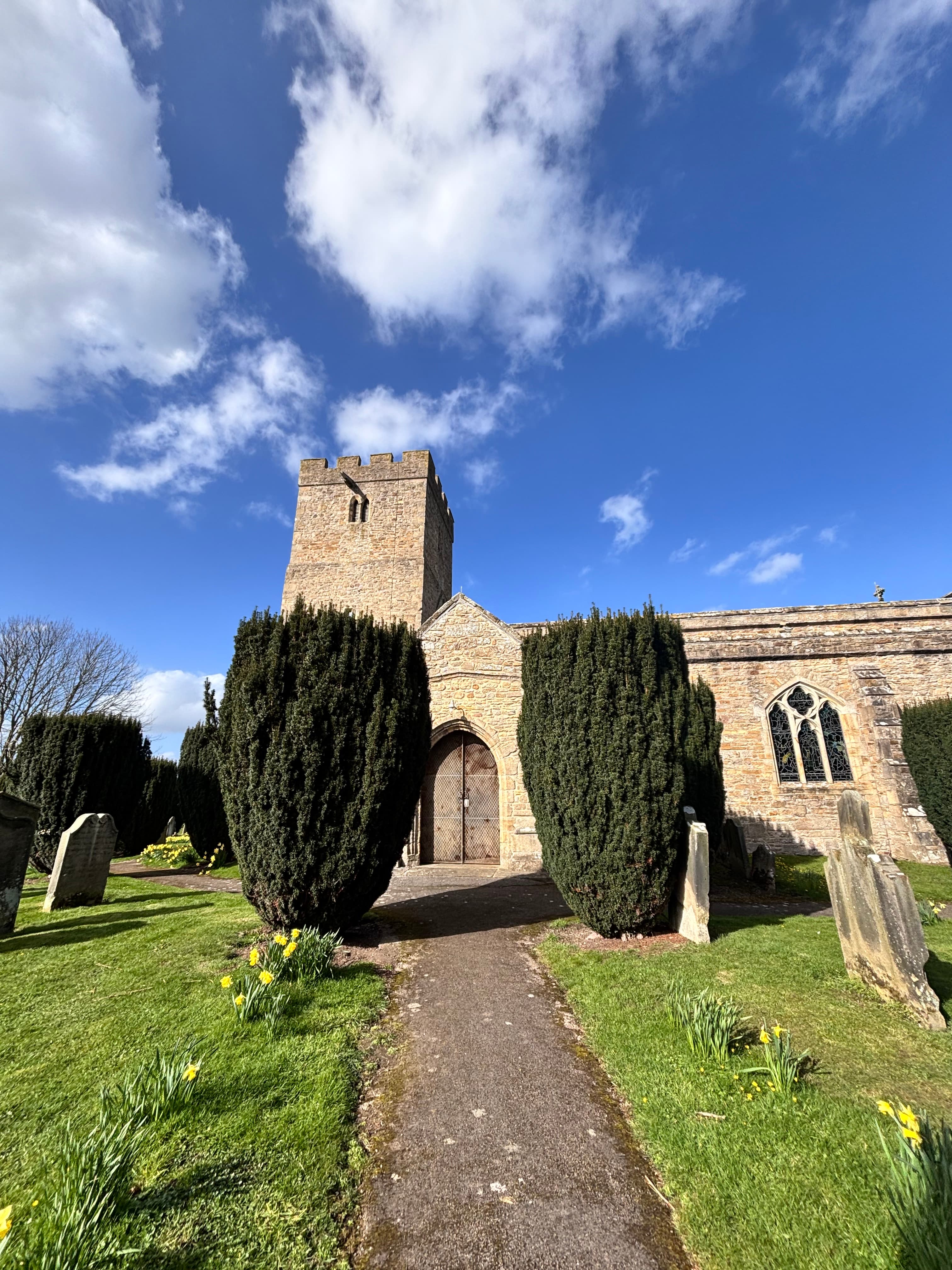 Historic stone church with tower surrounded by gravestones