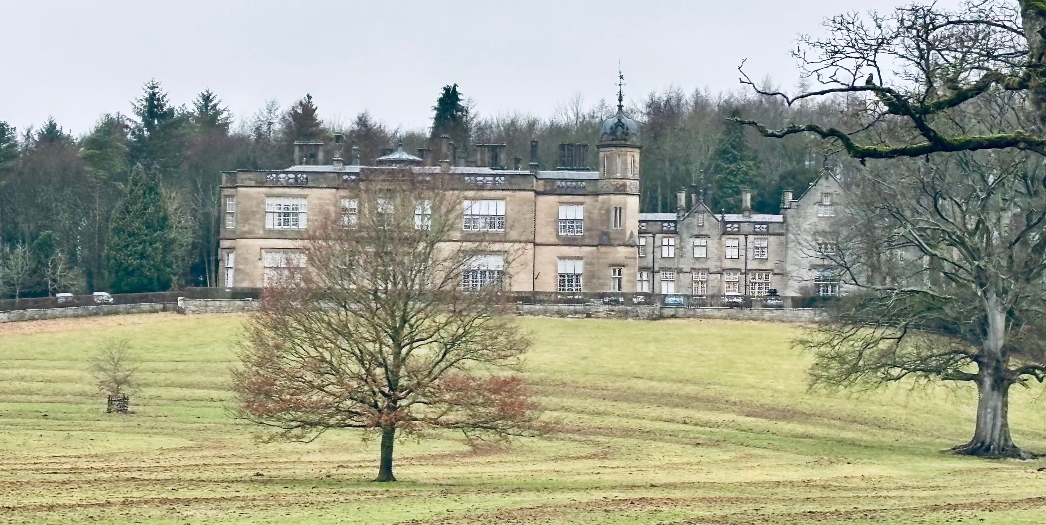 Historic stone manor house with turrets in lush countryside