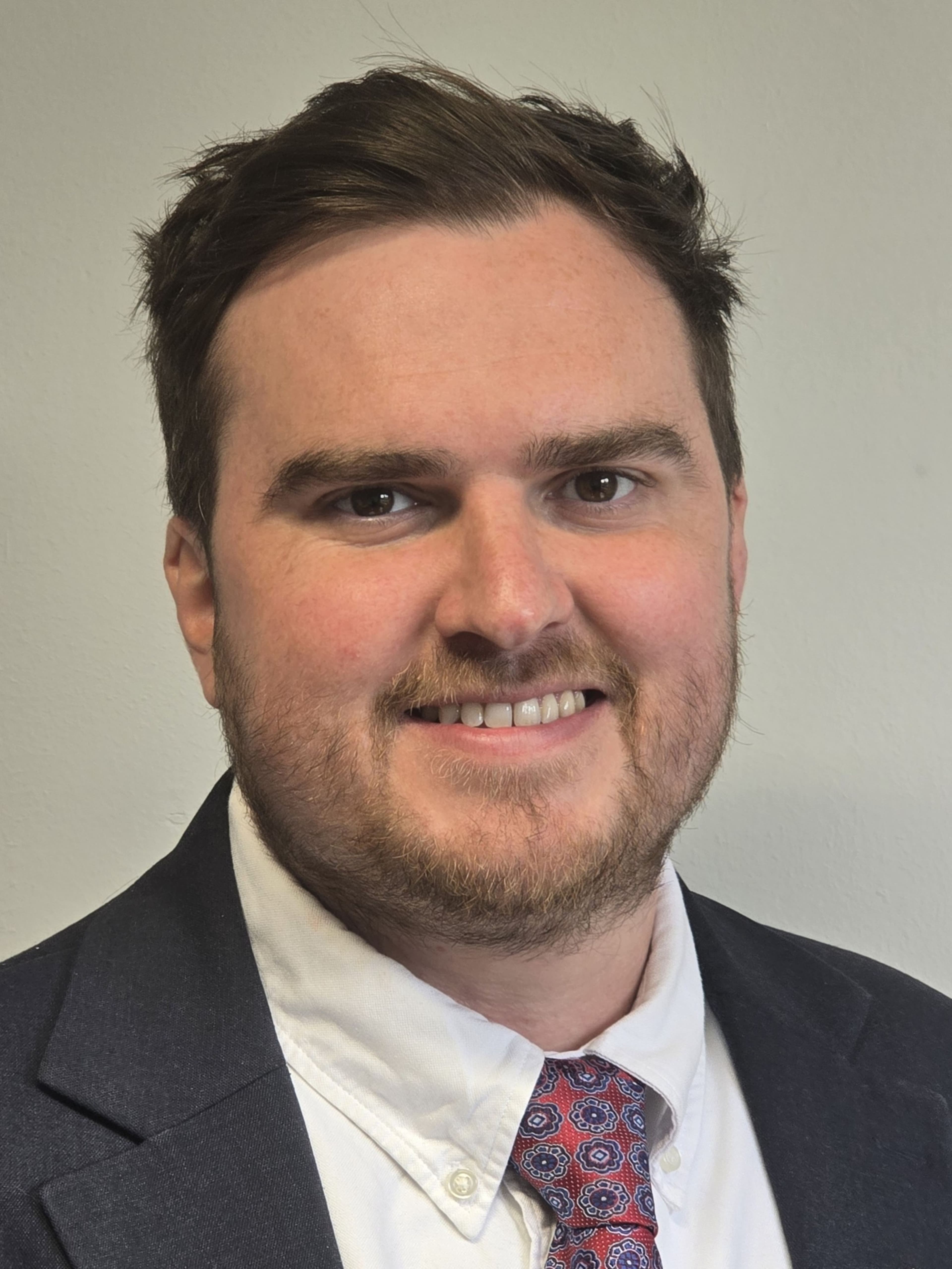 Smiling person in a suit with a white shirt and tie
