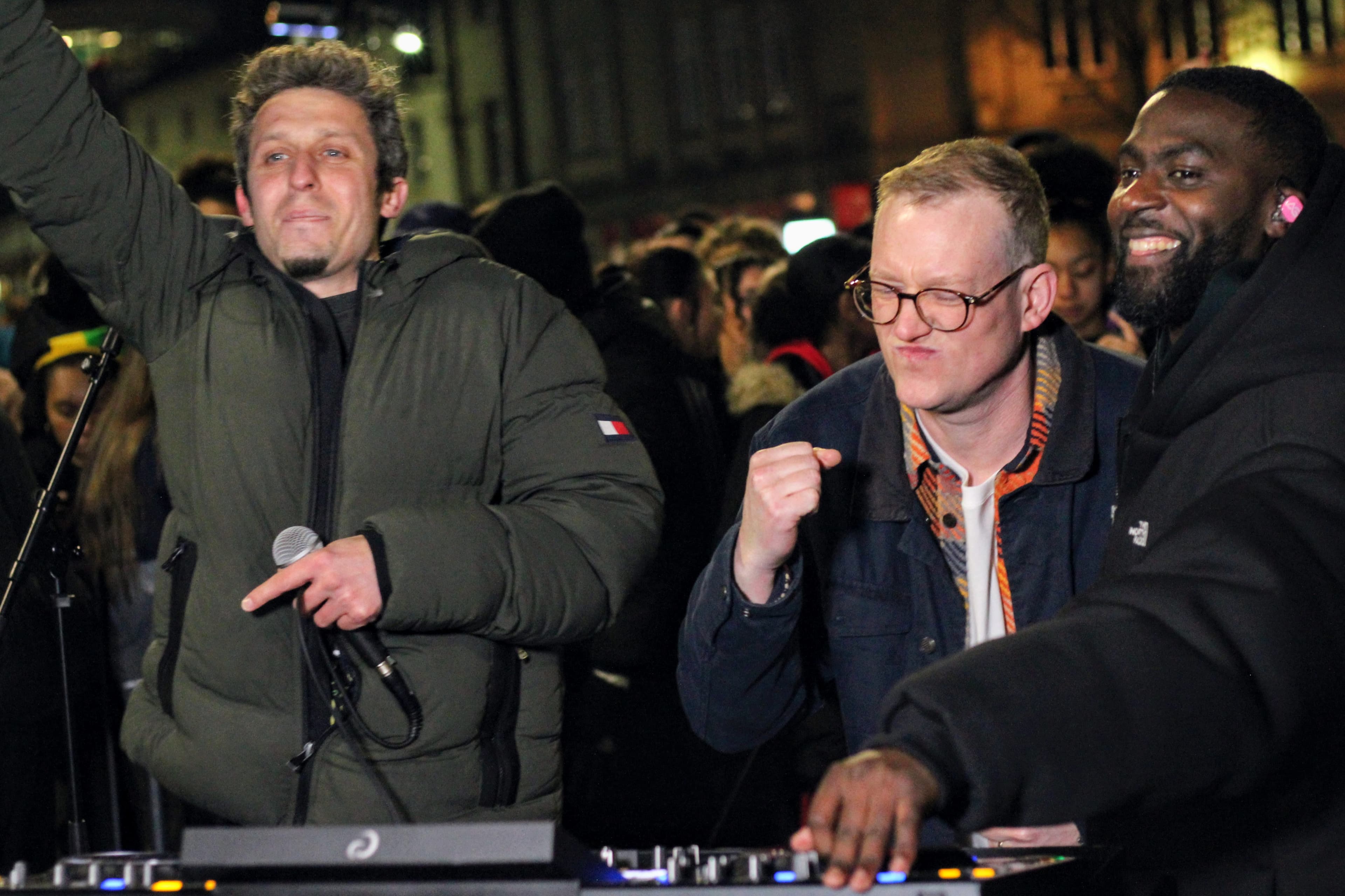 Three men enjoying a lively outdoor night event with a DJ