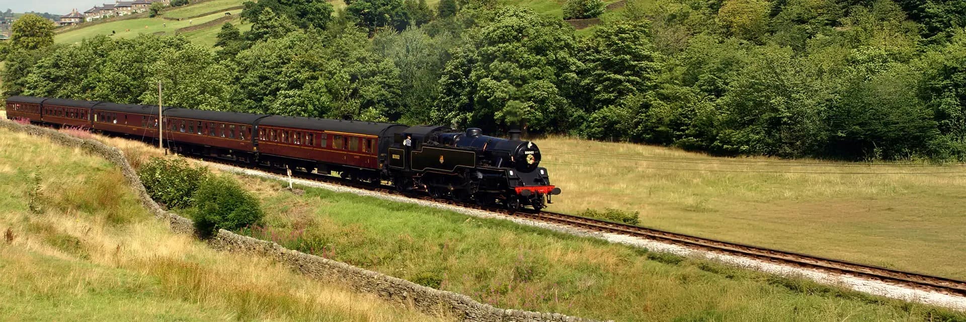 Historic steam train traveling through lush green countryside