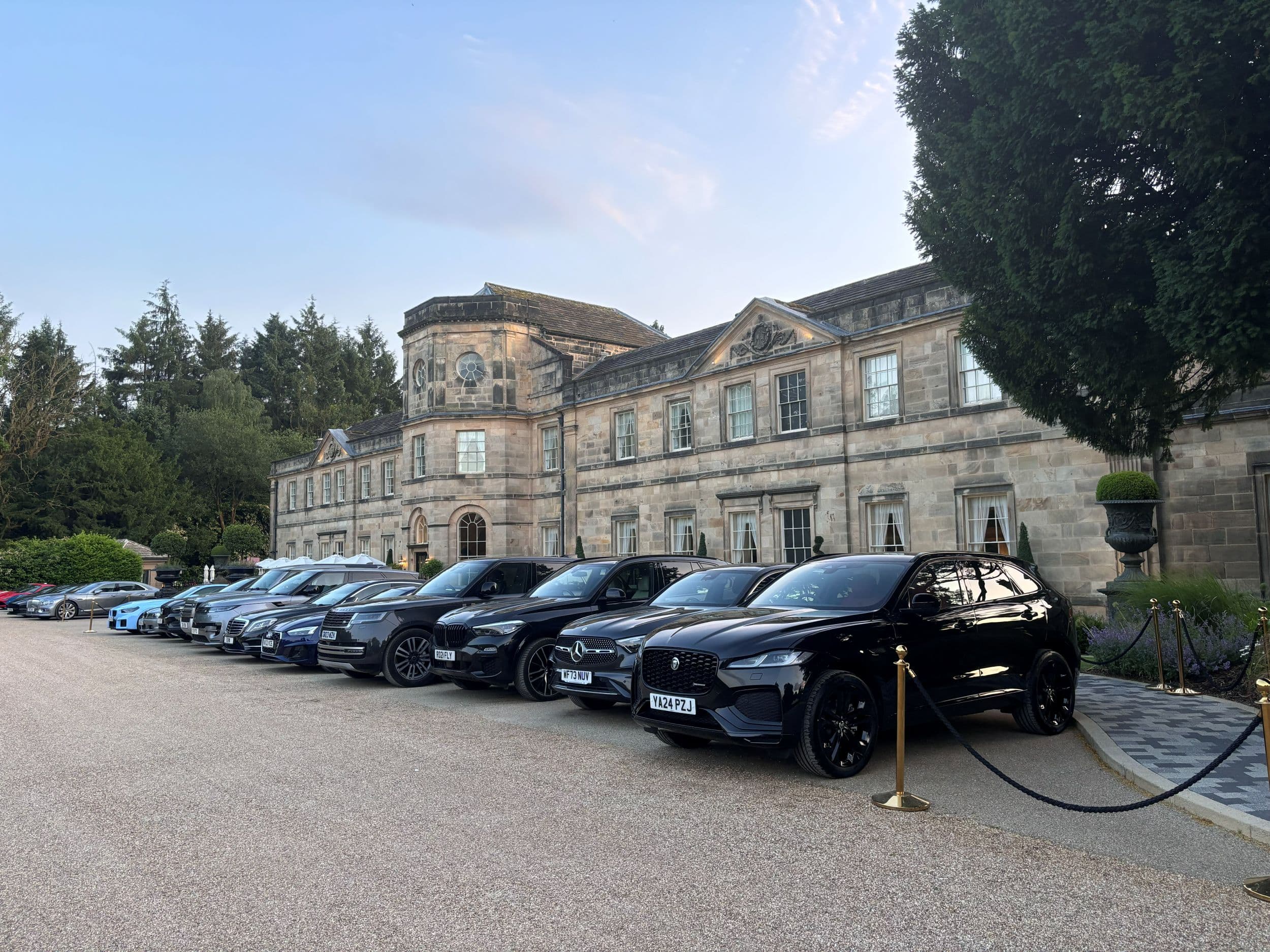 Historic stone manor house with parked luxury cars