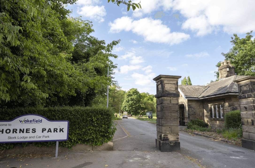 Entrance to Thornes Park with stone lodge and greenery