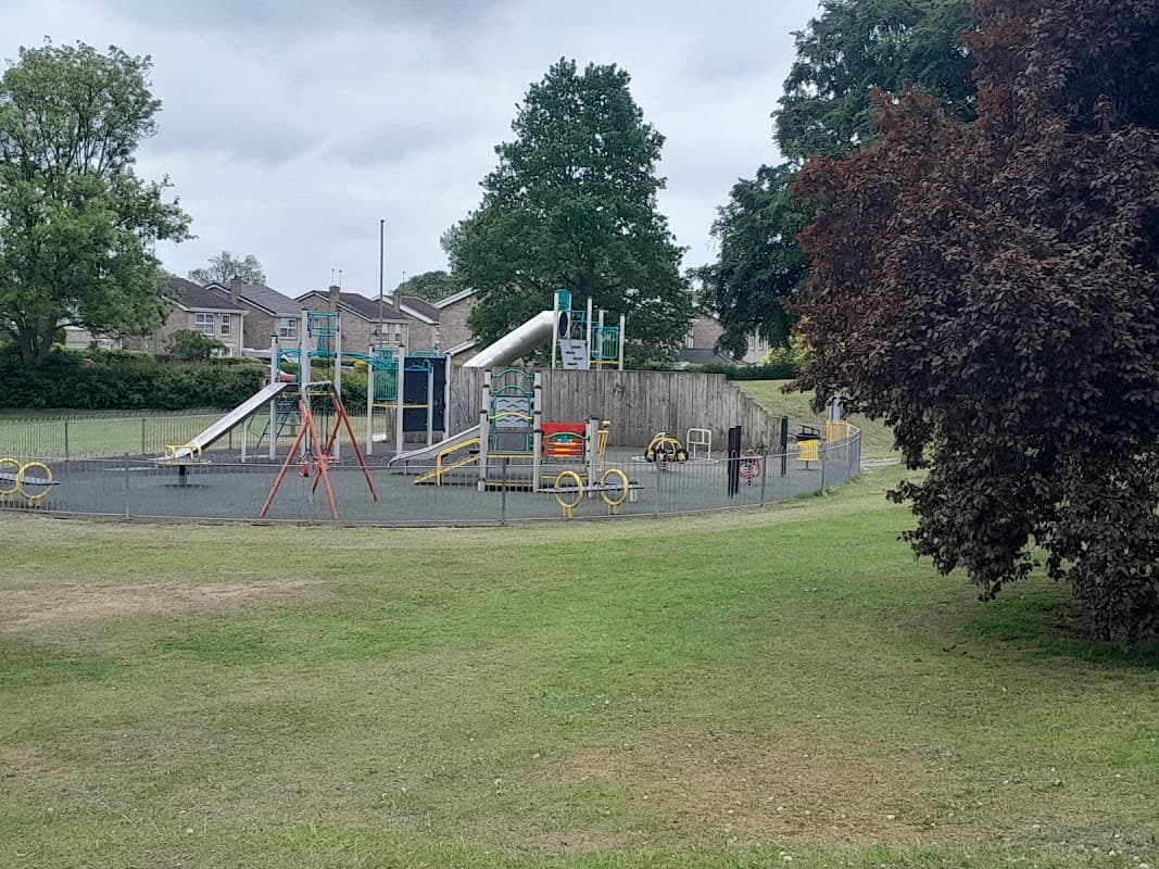 Playground featuring slides, swings, and climbing structures, surrounded by green grass and trees in Ackworth, Yorkshire.