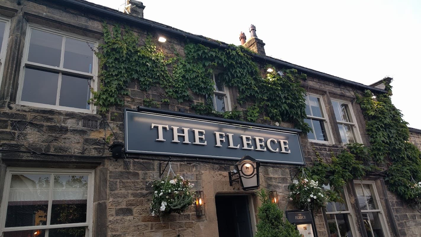 Historic stone pub with ivy-covered walls and a sign reading "THE FLEECE" in Addingham, Yorkshire.