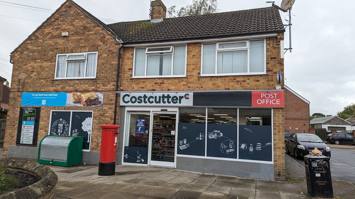 Costcutter and Post Office storefront with brick facade, large windows, and a red post box outside.