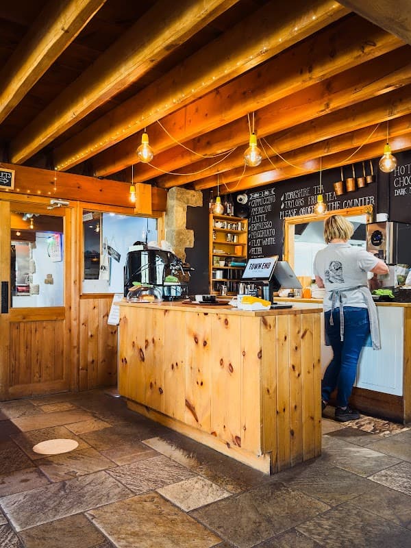 Wooden counter with menu board, warm lighting, and a staff member preparing food in a cozy shop atmosphere.