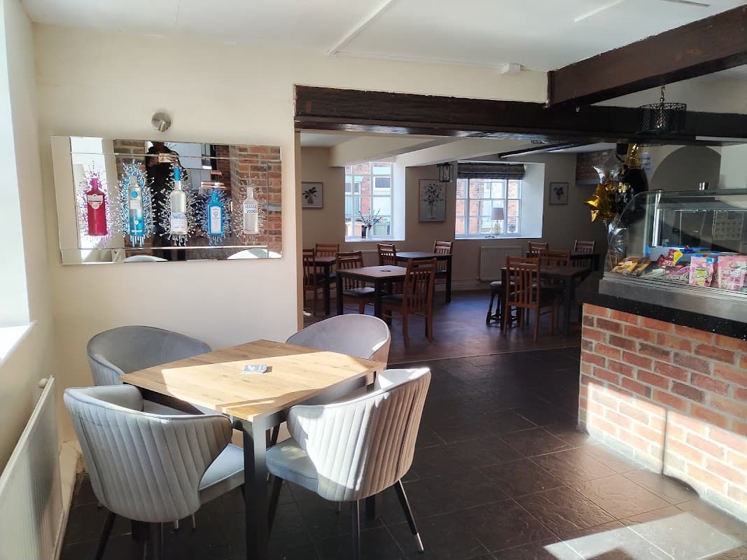 Bright interior of George & Dragon bar featuring wooden tables, chairs, and a mirror reflecting colorful decor.