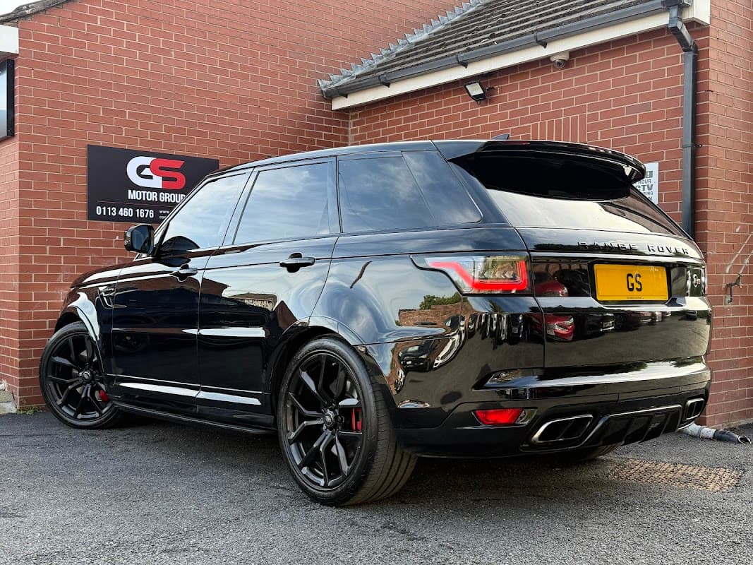Black Range Rover Sport parked outside GS Motor Group Ltd shop, with a sign featuring the company logo on the wall.