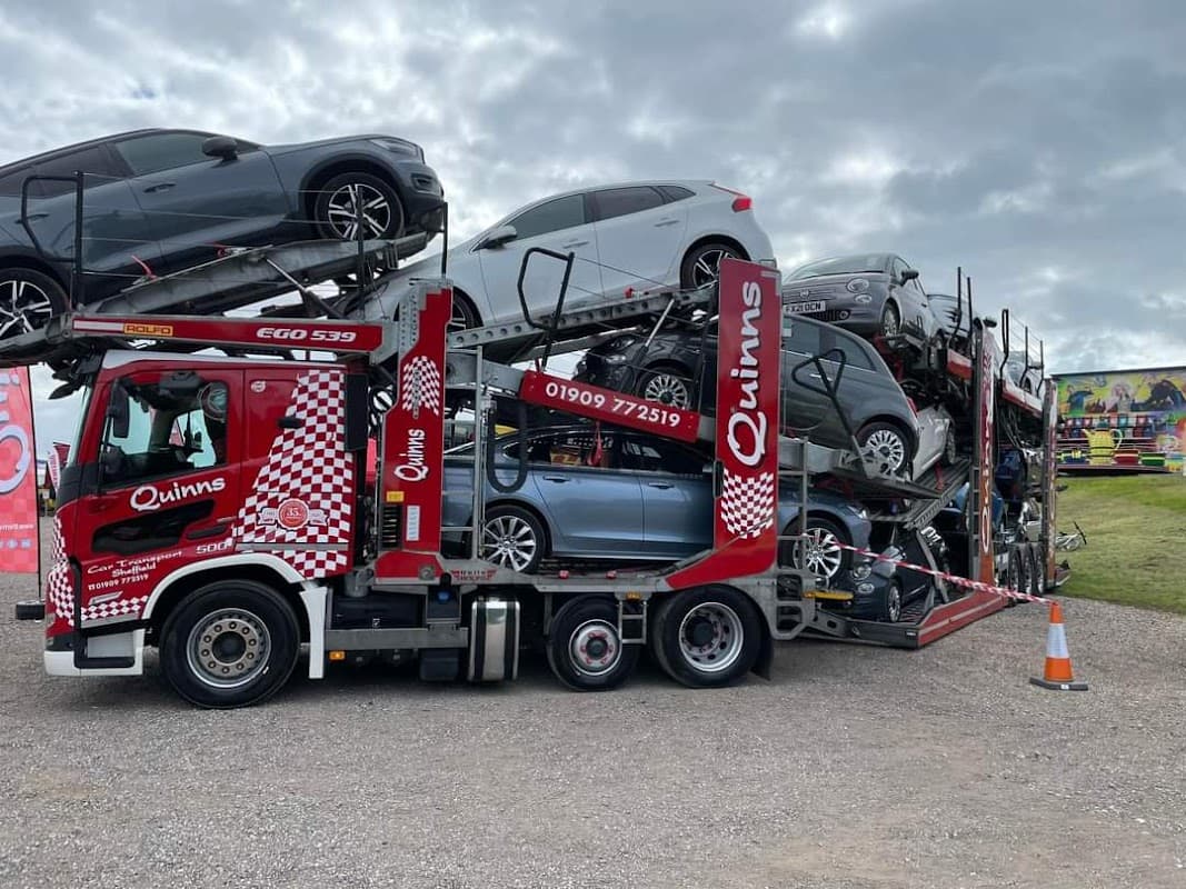 Quinns Car Transport truck loaded with multiple cars, parked in a Pay & Display area in Anston, Yorkshire.
