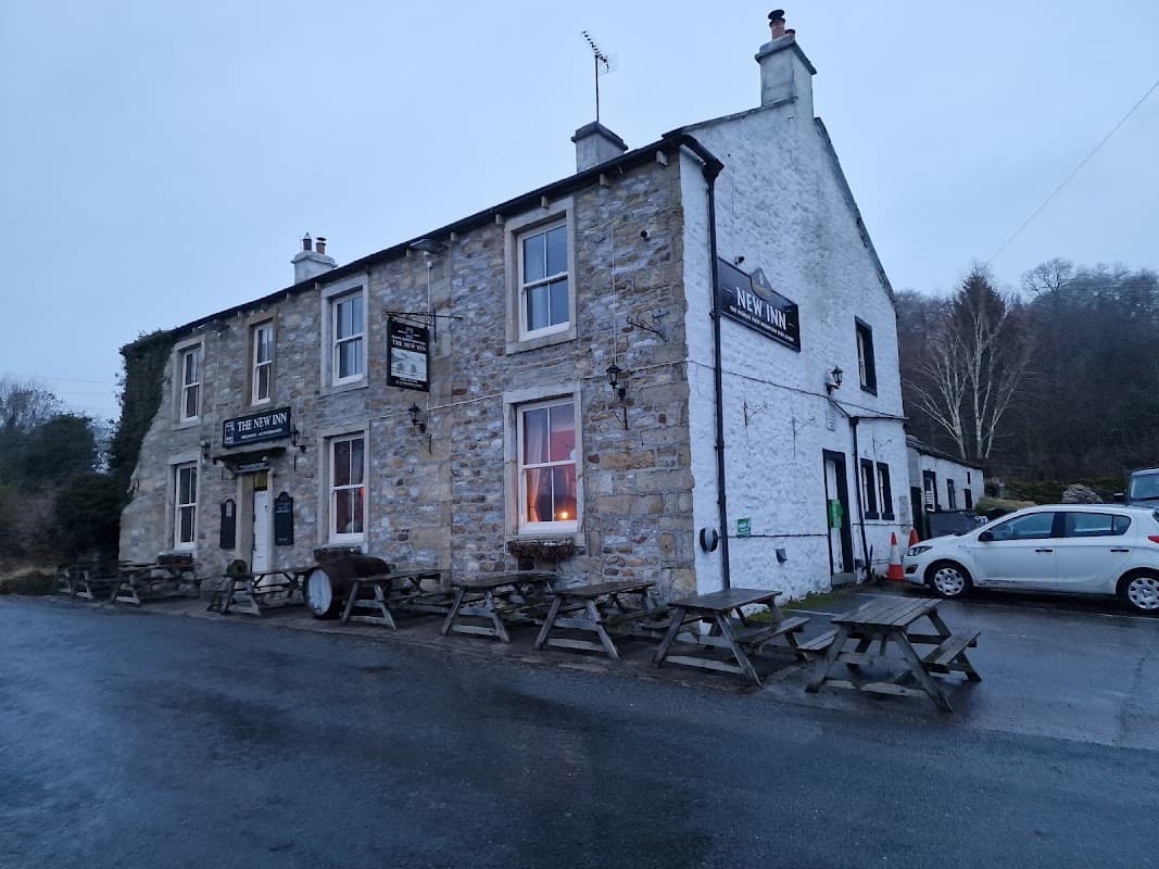 Pod Point Charging Station outside a stone building with a sign, picnic tables, and a parked car in a rural setting.