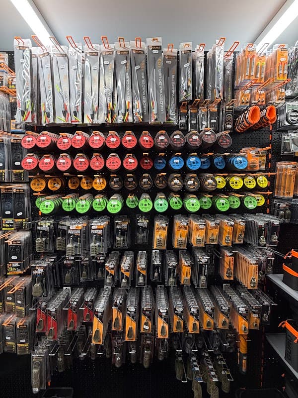 A wall display of fishing gear, featuring various lines, hooks, and tools in vibrant packaging at Aston Park Angling Centre.