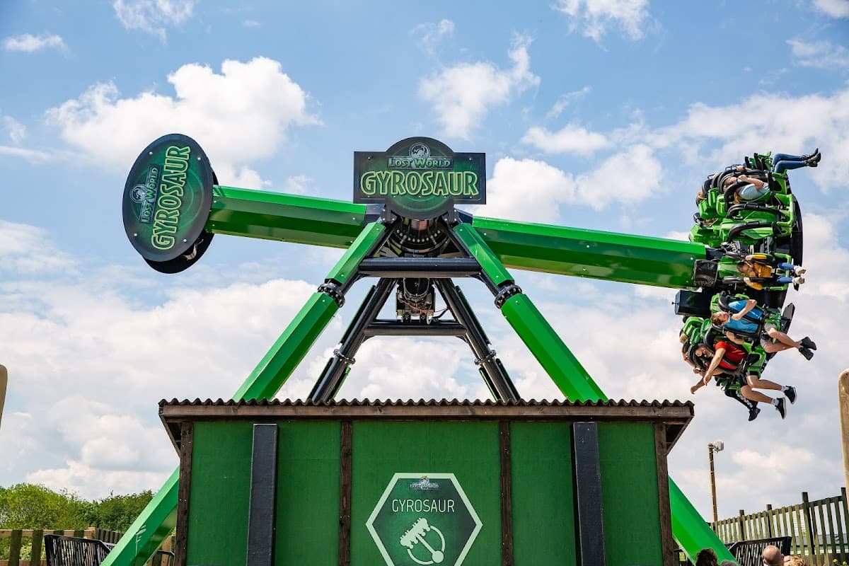 Thrilling Gyrosaur ride at Gulliver's Valley Theme Park, with excited riders suspended in the air against a blue sky.