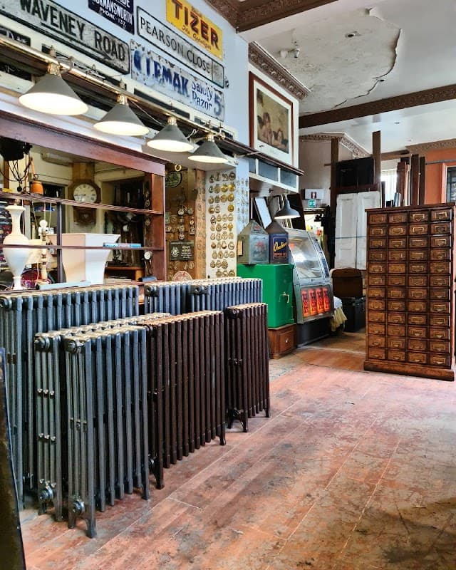 Antique shop interior featuring vintage radiators, wooden cabinets, signage, and a retro vending machine.