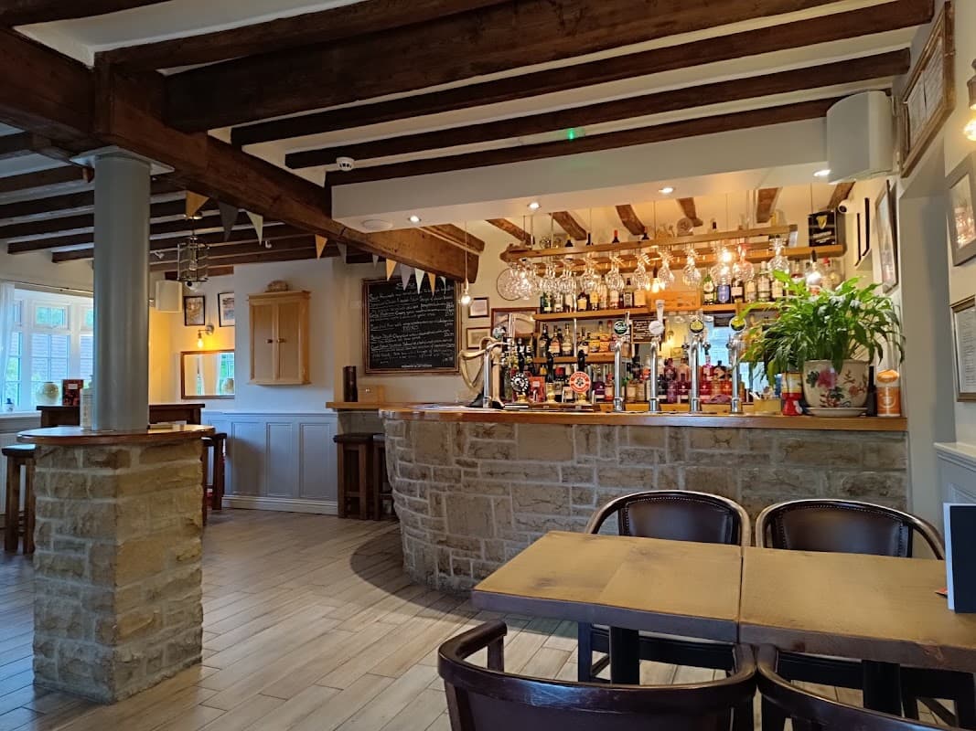 Cozy bar interior with wooden beams, a stone counter, colorful bottles, and a welcoming atmosphere in Bagby, Yorkshire.
