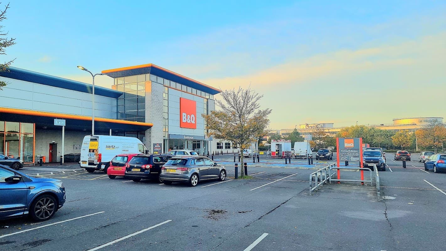 B&Q store with a car park filled with parked cars, trees, and clear blue sky in Balby, Yorkshire.
