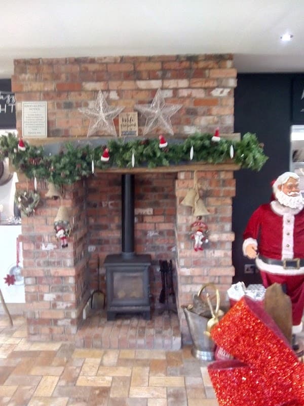Cozy brick fireplace adorned with garlands, stars, and holiday decorations, featuring a Santa figure nearby.