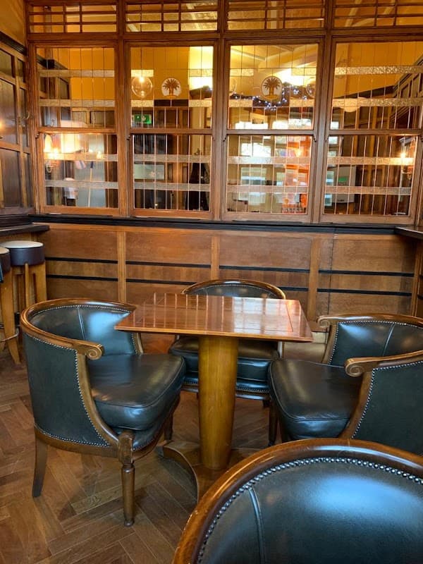 Wooden interior of "The Coach & Horses" pub, featuring a small table and leather chairs against a backdrop of glass panels.
