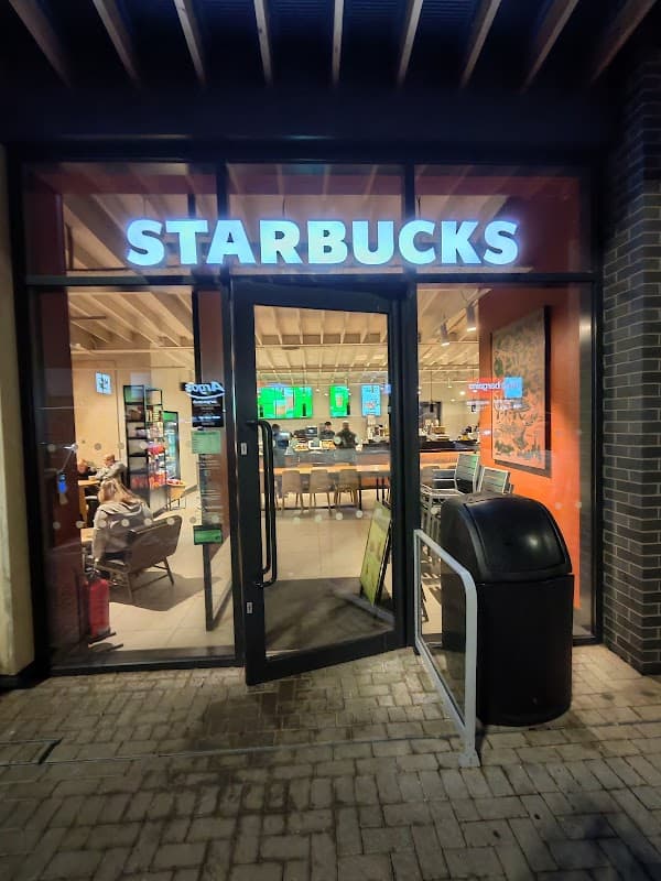 Starbucks entrance at Barnsley Retail Park, featuring outdoor seating and a visible trash bin nearby.