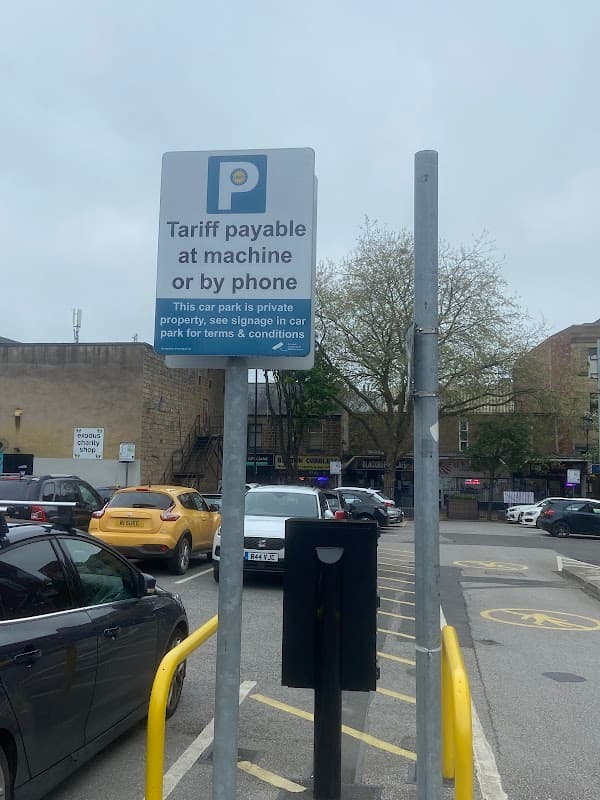 Sign indicating parking fees at Wellington House Private Car Park with vehicles and trees in the background.