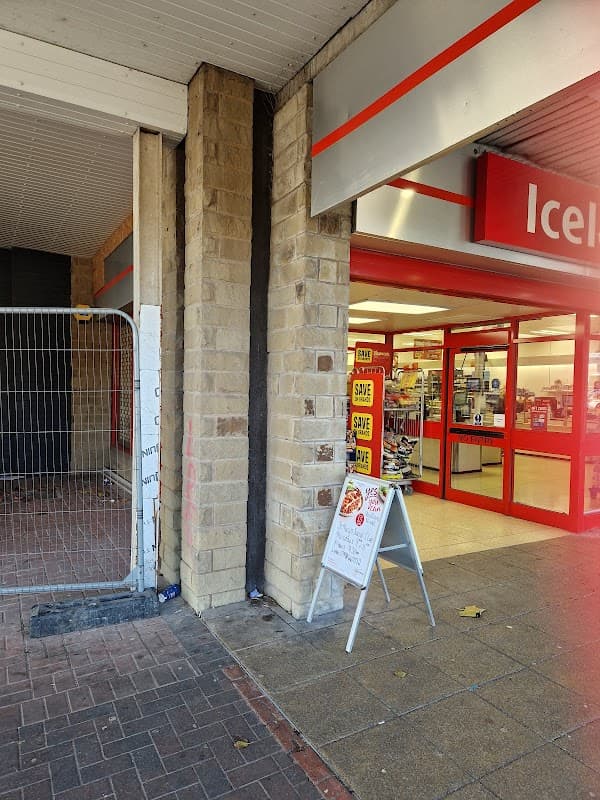 Entrance to Batley Shopping Centre with a signboard and safety notices. Red and white decor visible.