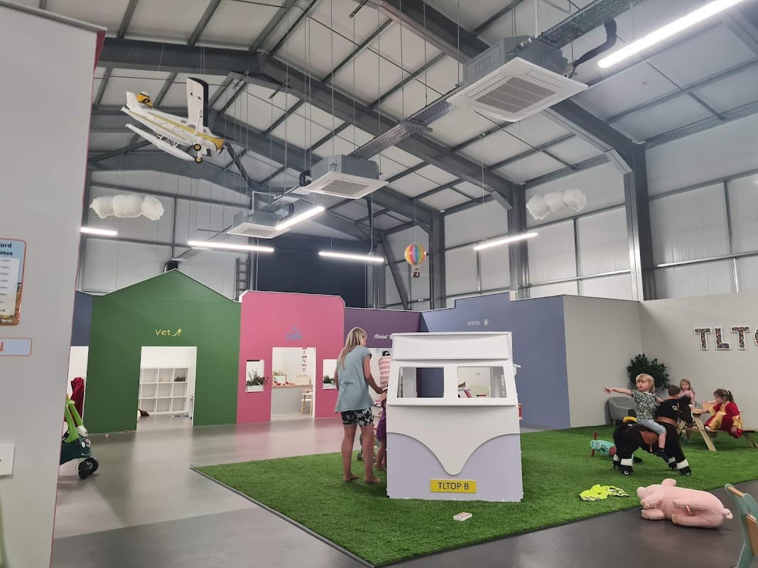 Indoor play area with colorful walls, children playing, and a model airplane suspended from the ceiling.
