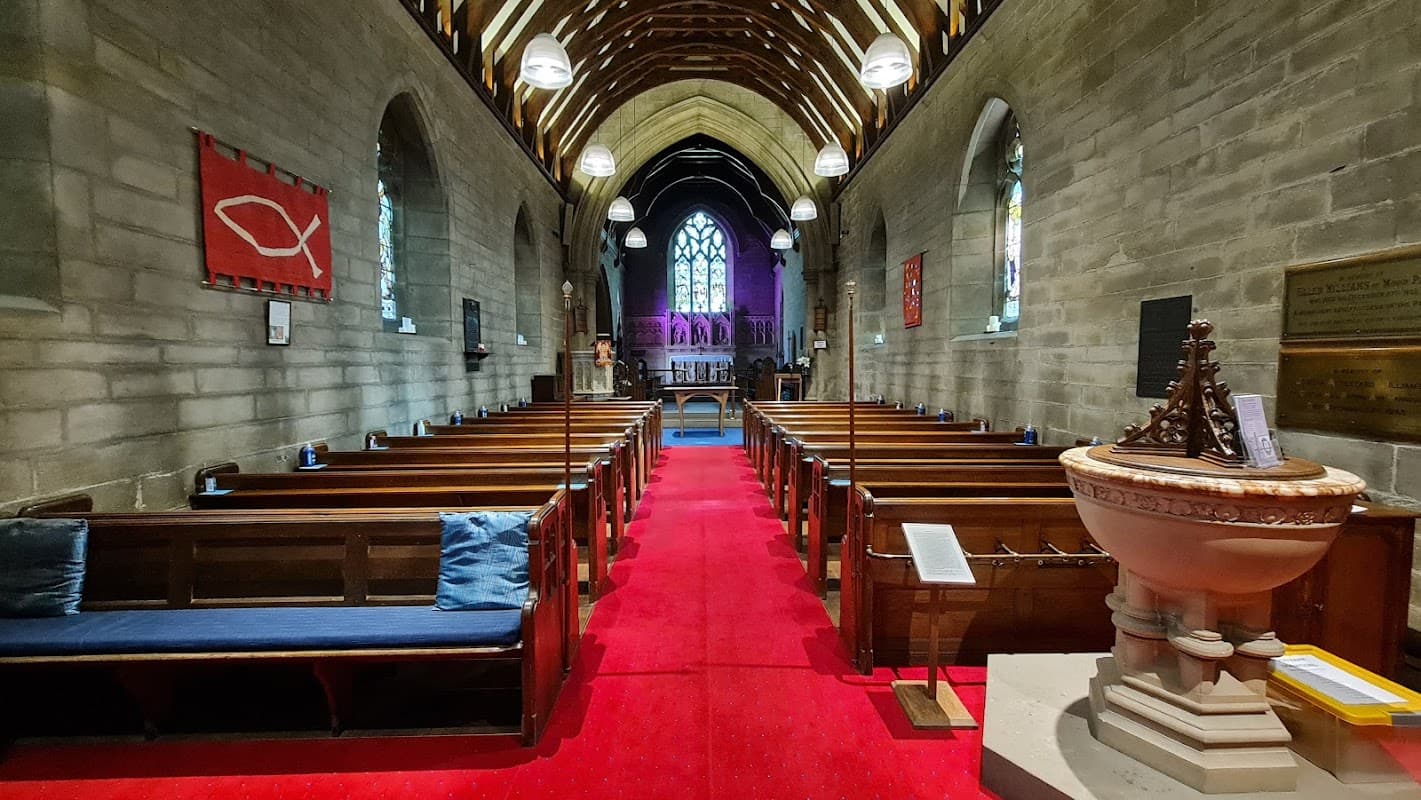 Interior of Beckwithshaw Village Hall featuring wooden pews, a red carpet, and stained glass windows.