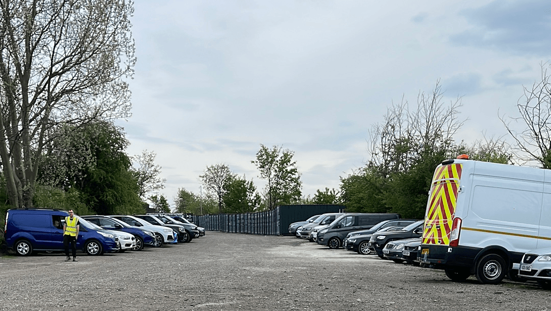 Pay & Display parking lot at Elland Road, with various parked cars and a parking attendant in a reflective vest.