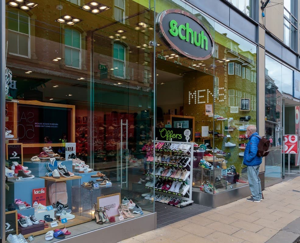 Shoe shop entrance with various shoe displays and a customer browsing outside in Beeston, Yorkshire.