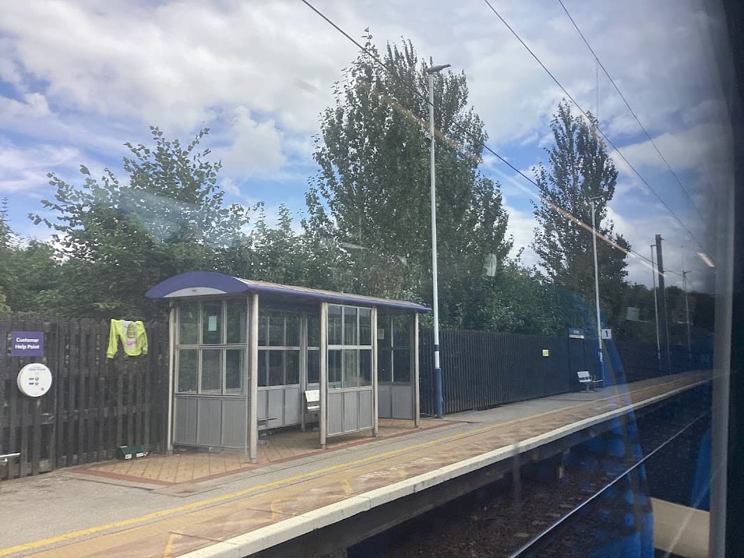 Bus stop shelter with seating, surrounded by trees, under a cloudy sky at Bentley, Yorkshire.