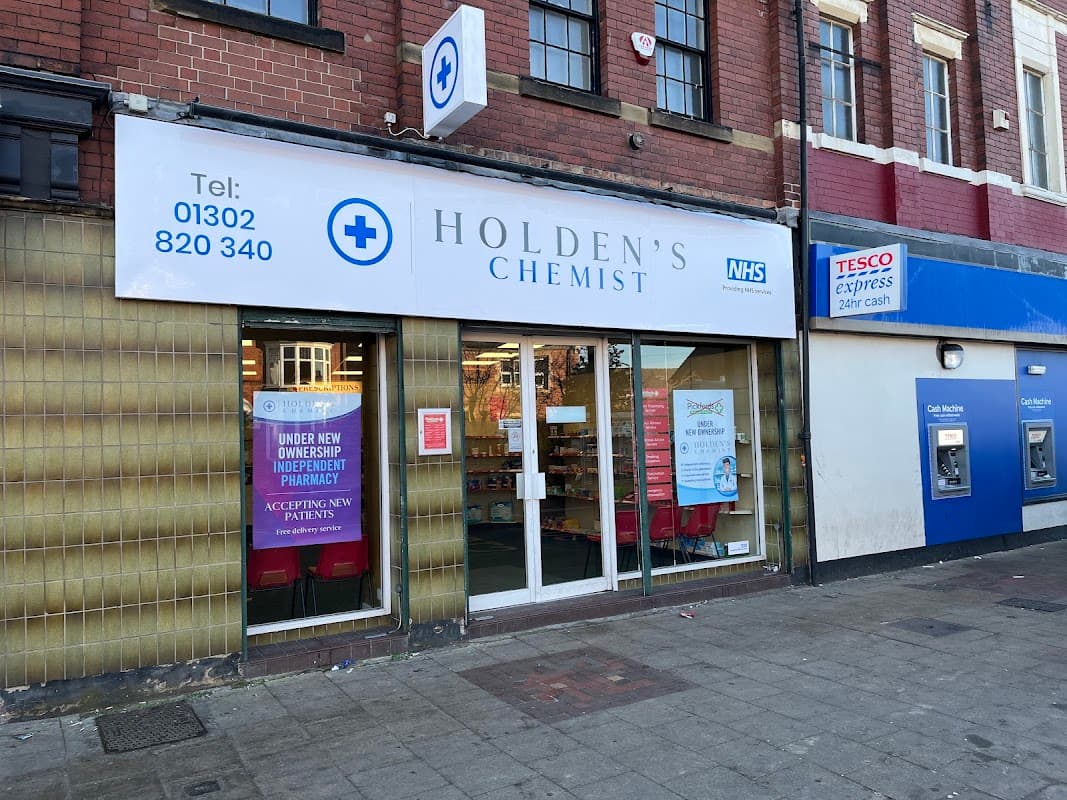 Holden's Chemist storefront in Bentley, featuring a large sign, NHS logo, and promotional posters.