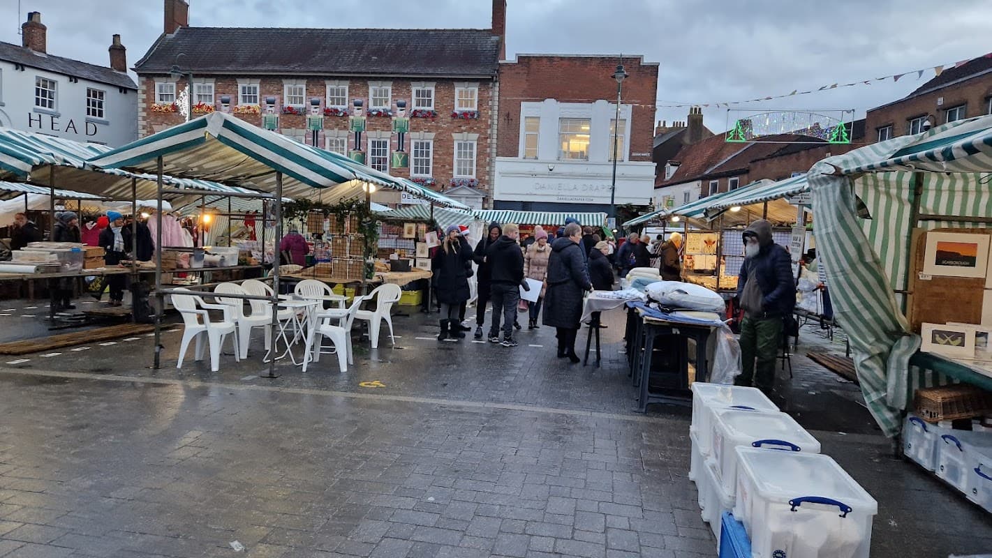 Busy market scene with striped canopies, vendors, and shoppers in a car park setting in Beverley, Yorkshire.