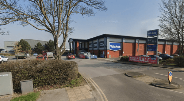 Wickes store in Beverley, Yorkshire, with parked cars, trees, and clear blue sky. Sale banner visible.