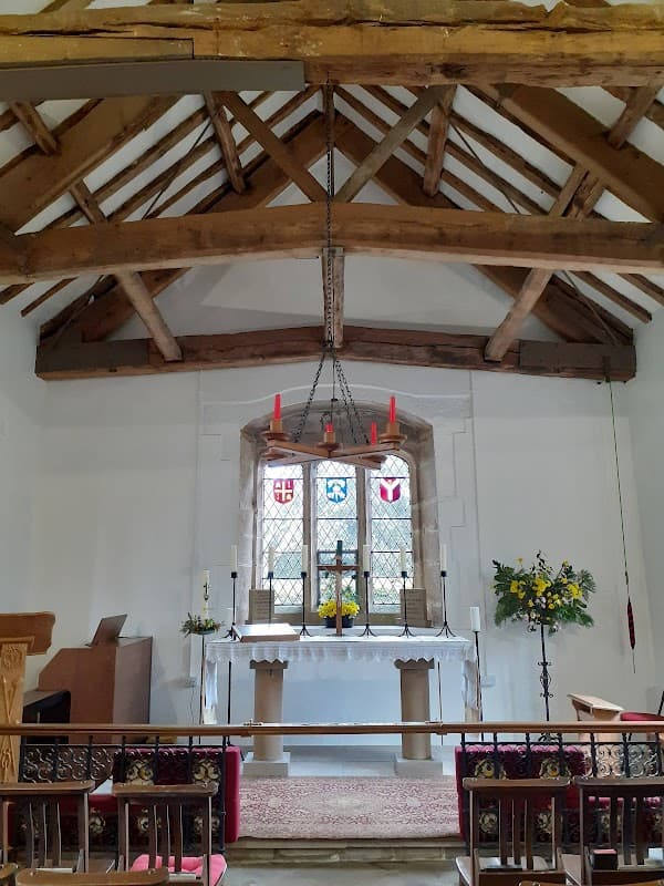 Interior of Bewerley Grange Chapel featuring wooden beams, stained glass windows, altar, and floral arrangements.