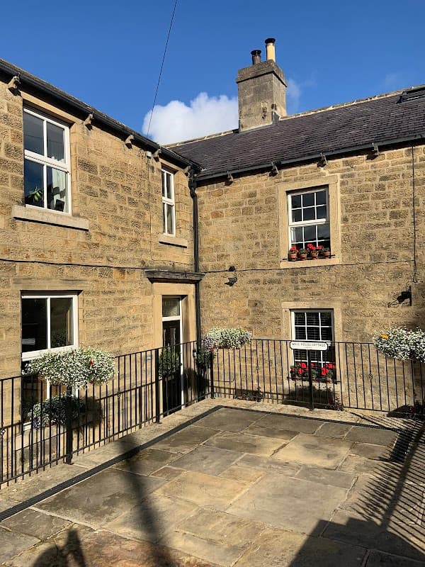 Stone cottage with flower boxes, a small patio area, and a clear blue sky in Bewerley, Yorkshire.