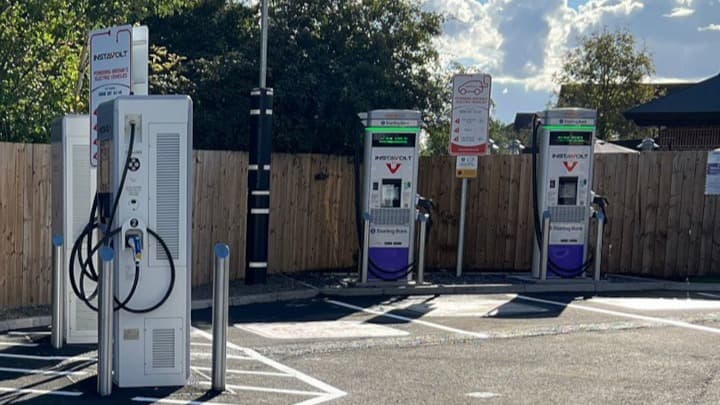InstaVolt charging stations with multiple chargers, surrounded by wooden fencing and clear blue skies in Bilbrough, Yorkshire.