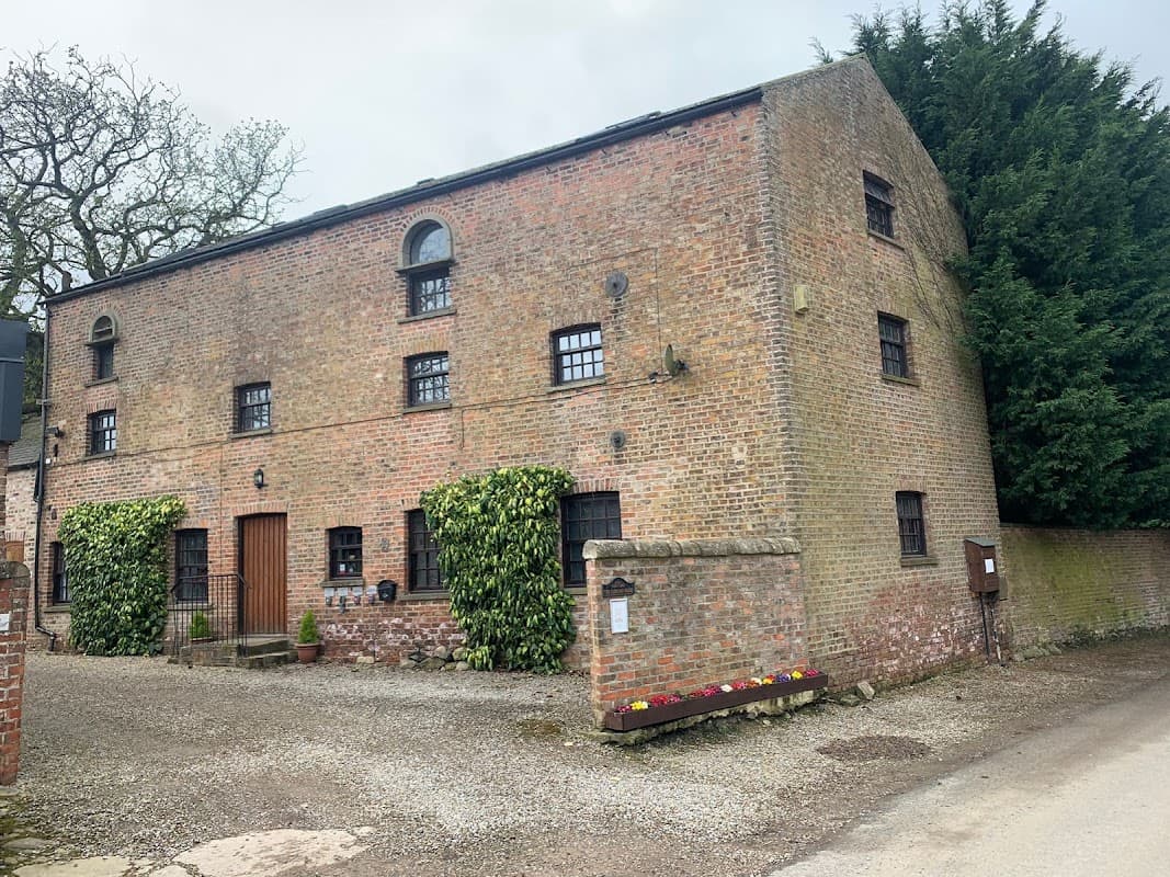 Brick building with arched windows, ivy-covered walls, and a gravel path in Bilbrough, Yorkshire.
