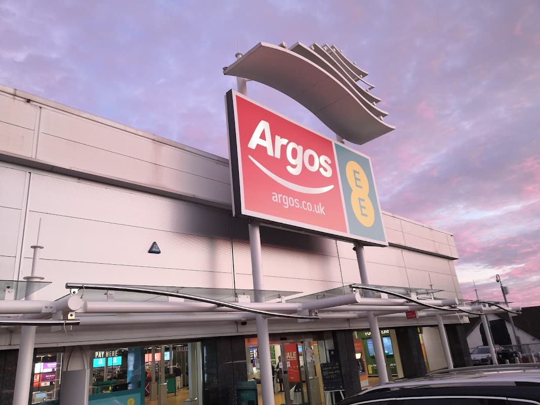 Argos storefront with large sign, featuring a pink and blue sky in the background at dusk.