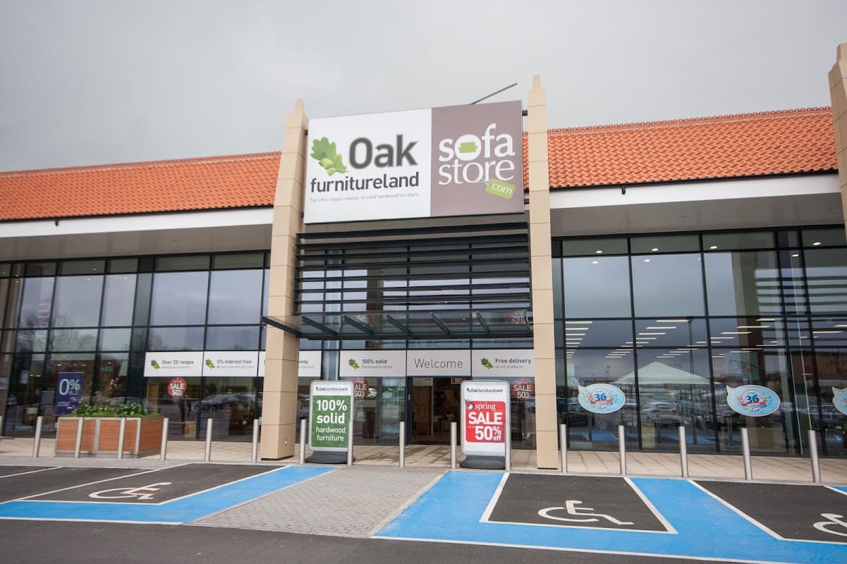 Entrance to Oak Furnitureland with large signage, accessible parking, and promotional sale banners.
