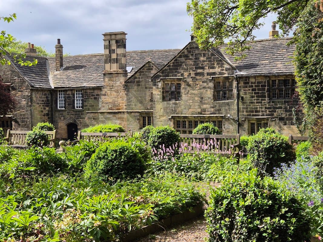 Historic stone building surrounded by lush gardens and greenery at Oakwell Hall Country Park.