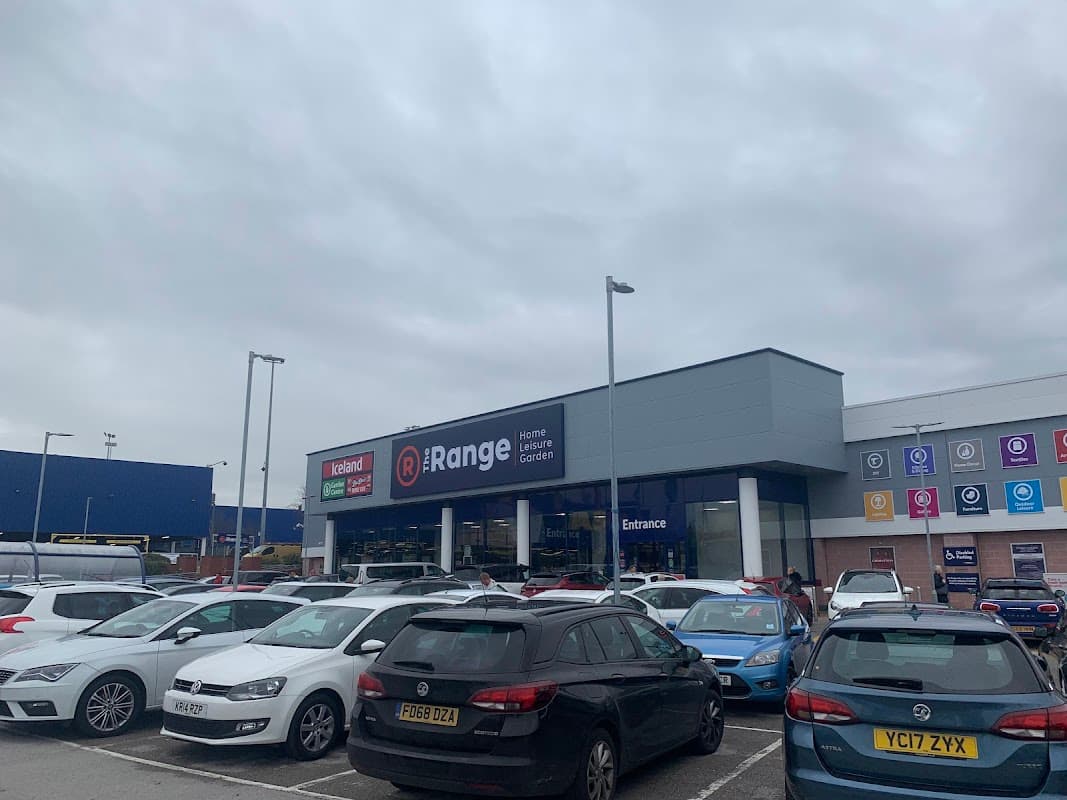 The Range store exterior with a large sign, surrounded by parked cars under a gray sky.