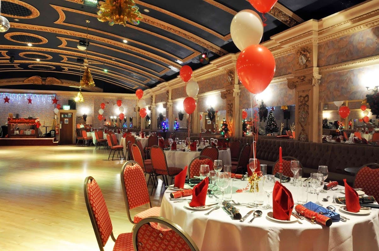 Elegant banquet hall decorated with red and white balloons, festive table settings, and holiday decor.