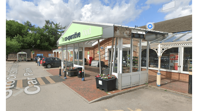 Co-operative food store entrance with a car park, flower planters, and blue sky in Bolsterstone, Yorkshire.