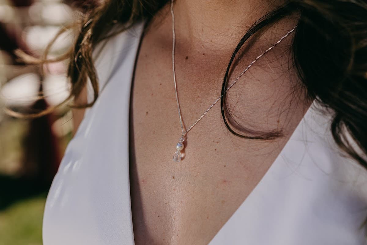 Delicate silver necklace with a small pendant, worn on a bare collarbone, highlighting a natural, elegant look.