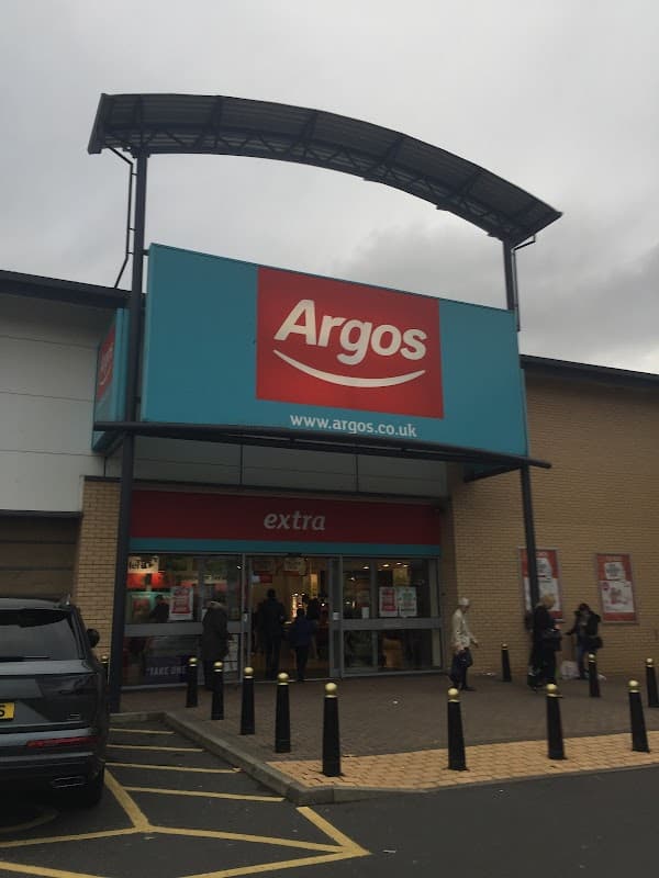 Argos store entrance with large red sign, shoppers outside, and a cloudy sky overhead in Bradford, Yorkshire.