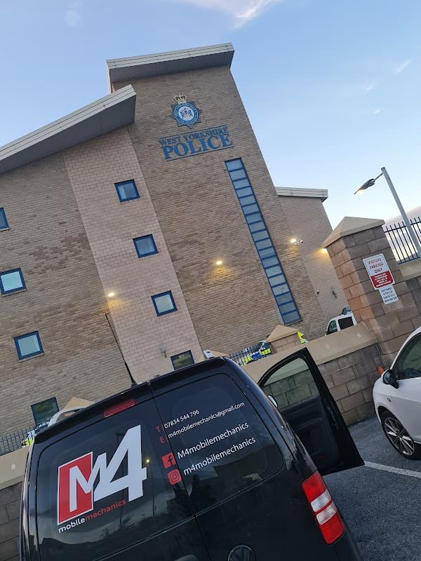 Pay & Display car park with a police station in the background; a parked van with contact information visible.