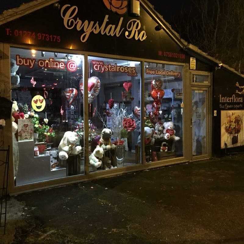 Bright storefront of Crystal Roses Florist featuring flowers, balloons, and plush toys, with a welcoming display.
